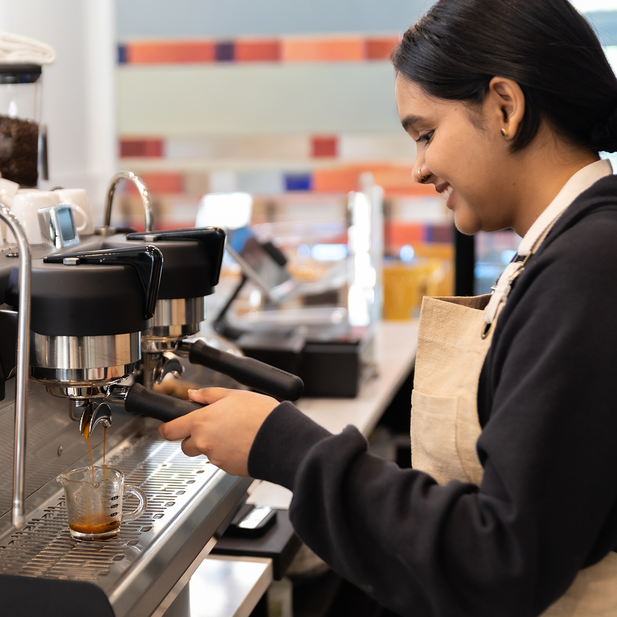 High-end espresso machine in a bright cafe setting, professional barista pulling a shot, clean aesthetic, warm Mediterranean lighting