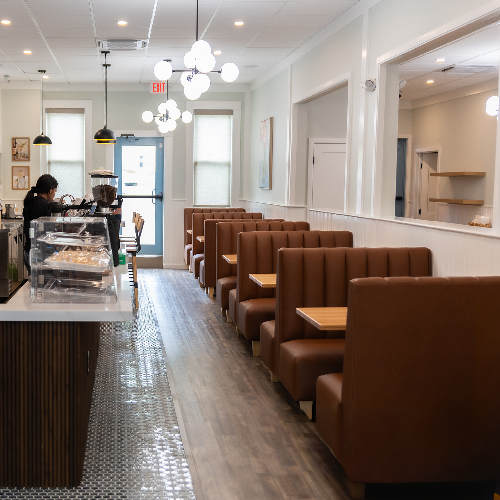 Warm, inviting interior of a Mediterranean-style cafe, natural light, elegant seating, olive branches, clean white walls